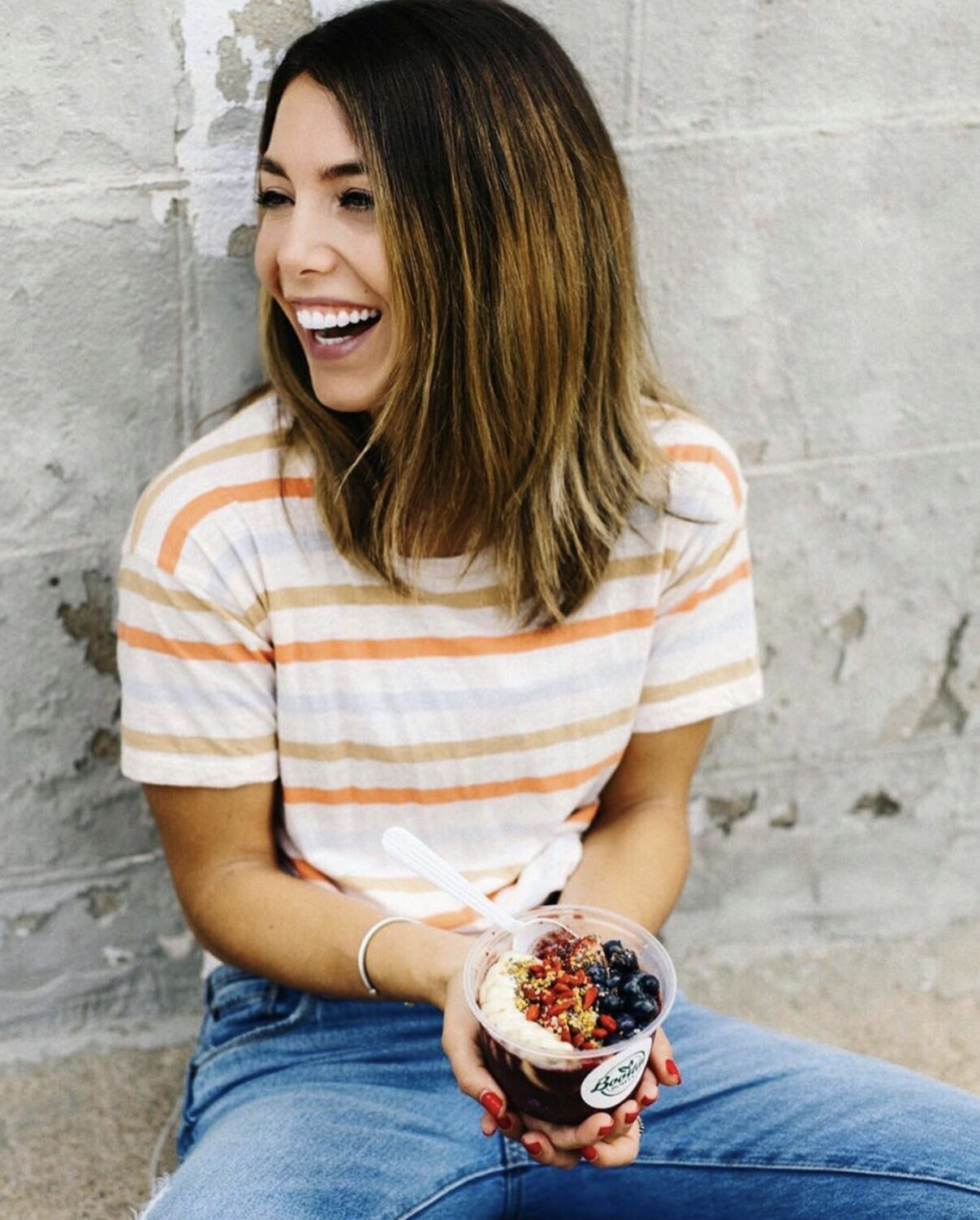 Jenna laughing with an açaí bowl in hand